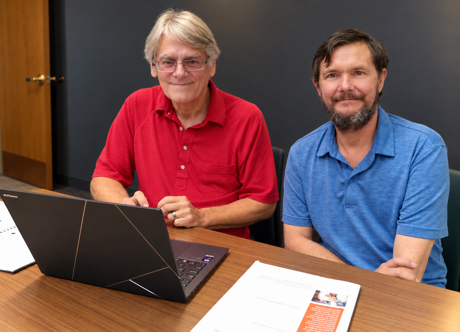 Eddie Harbert and his husband Jason at a table with a laptop